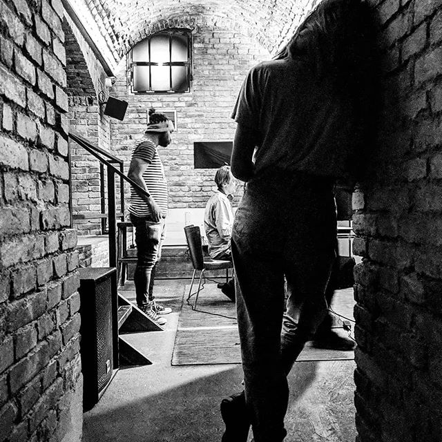 Black and white image of two men and a woman listening to music in a basement club.
